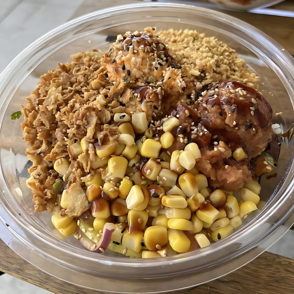 Rollrritto Poke Bar poke bowl with corn, crispy onions, and two scoops of protein drizzled with sauce.