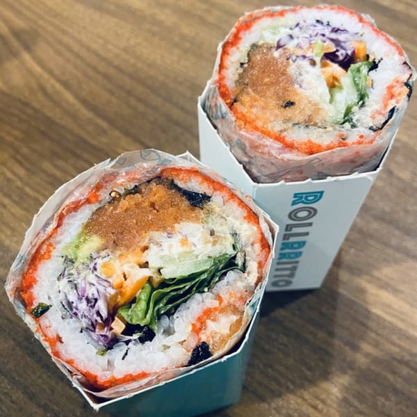 Two Rollrritto poke burritos, filled with rice, fish, and vegetables, in branded holders.